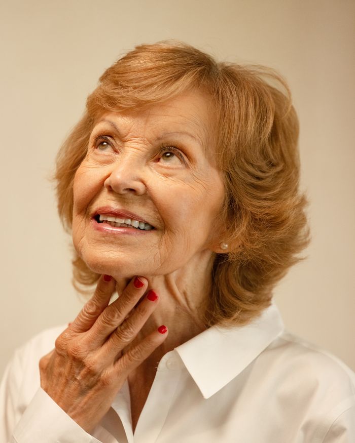 Mujer sonriente de cabello rojizo cuidando la piel de su cuello